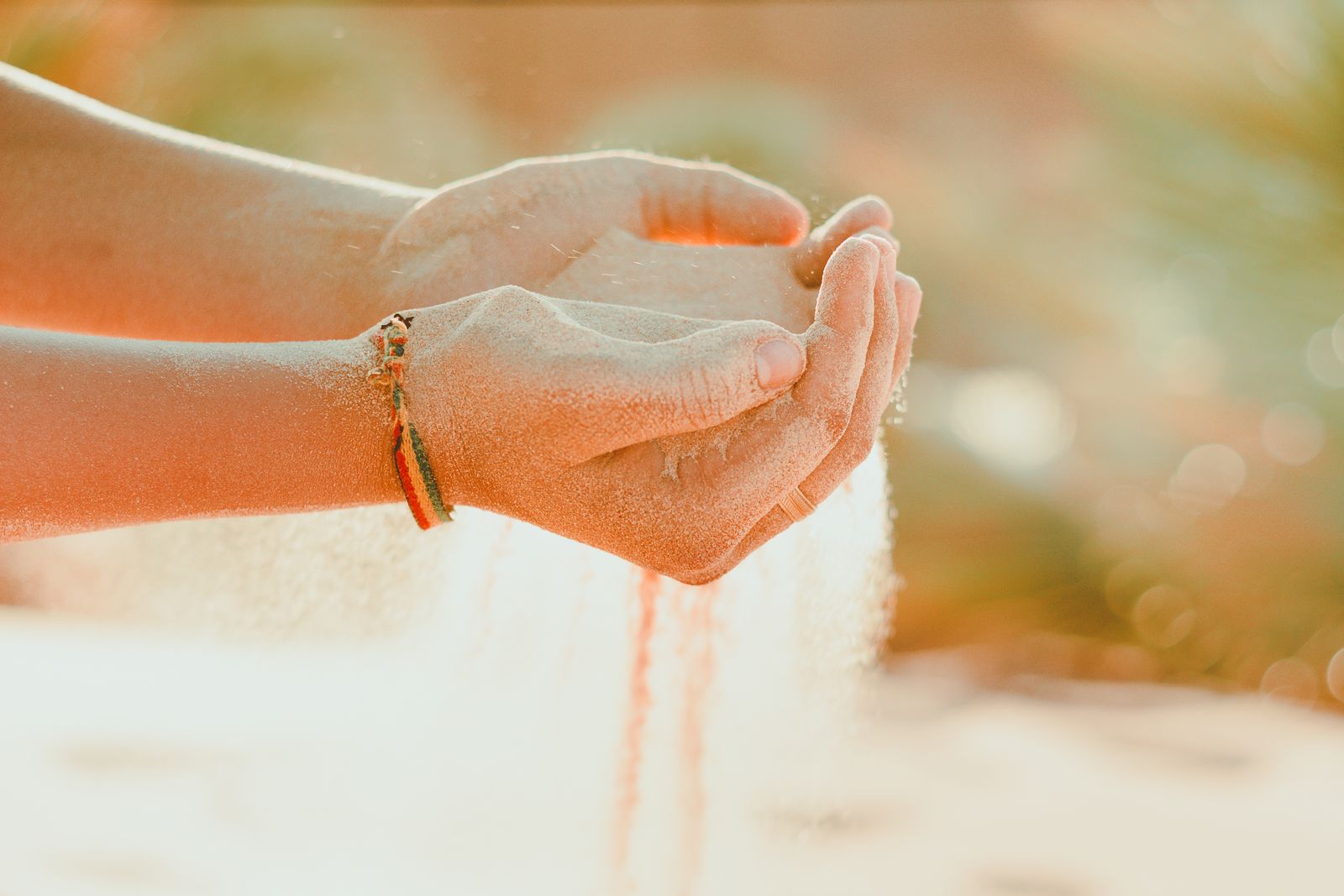 Open hands cradling sand in warm golden light