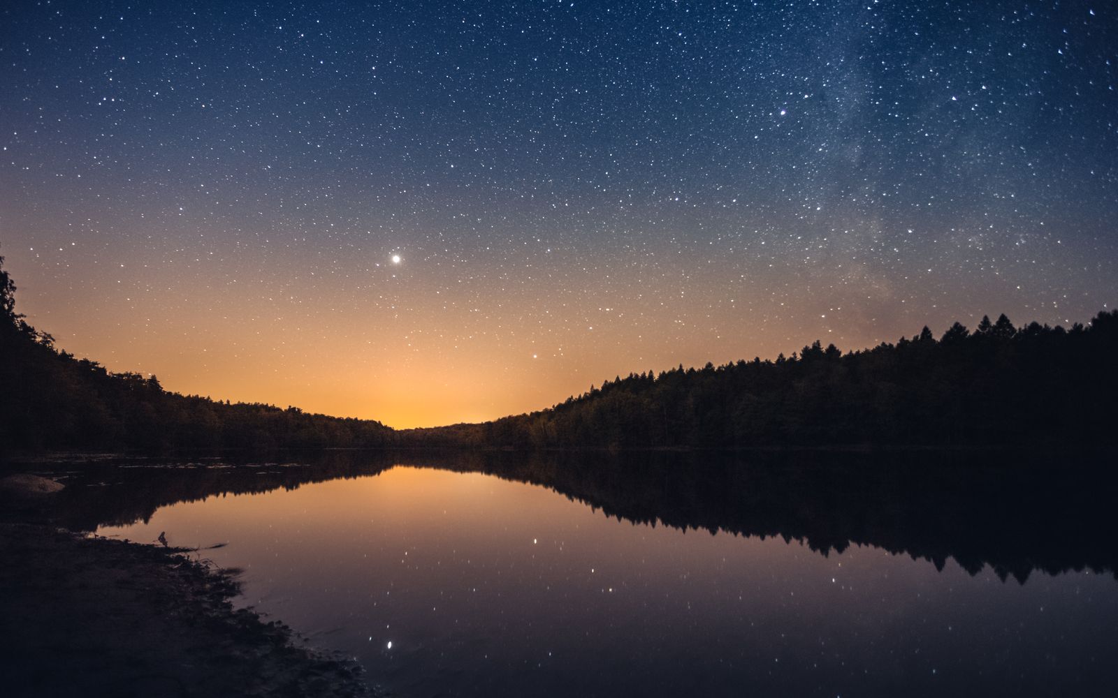 A starry night sky reflected in a still lake