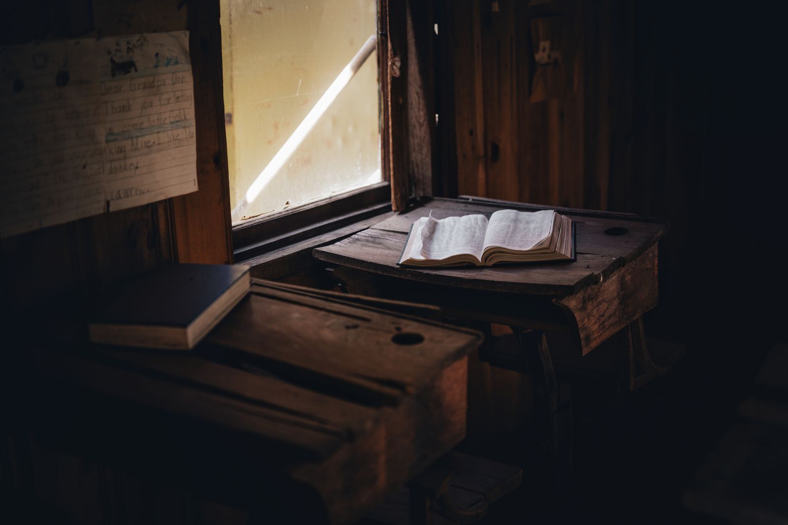 An open book on a rustic desk in soft window light